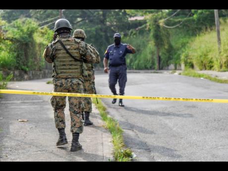 Members of the security forces at the scene where reputed gang leader, Christopher ‘Dog Paw’ Linton was shot and killed on Monday. 