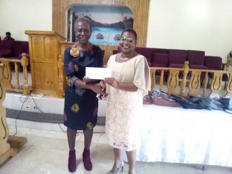 Credit: Rasbert Turner Pauline Beecher (left) presents a cheque to Simon Primary and Infant School principal Nova-Dean Samuels-Lee.