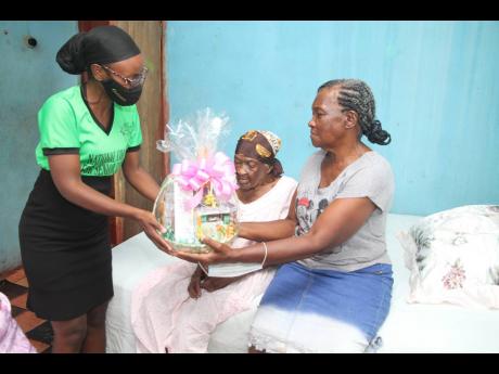 Phyllis Black (right) collects a gift package from Toshane Young (left) on behalf of her mother Louisea ‘Mama Lou’ McDonald of Boghole, Clarendon.