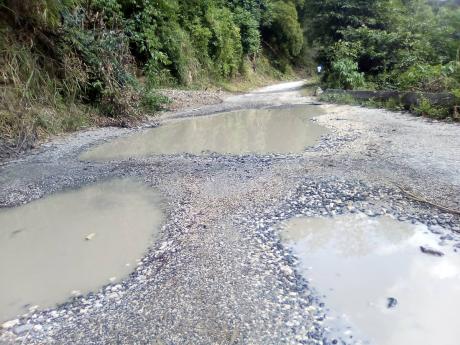 Huge potholes riddle the Bamboo Corner road in St Catherine, causing damage to vehicles and making transportation difficult.
