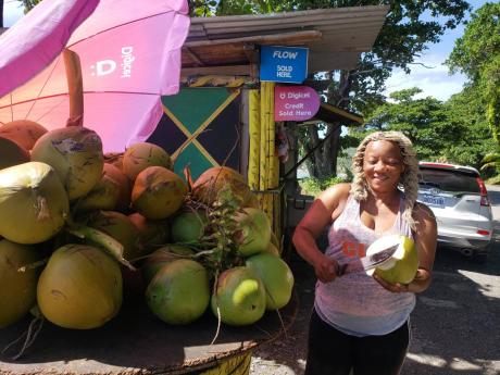 Annecia Lawson chops a cool coconut for a customer at her shop which is opposite the picturesque Roselle Falls.