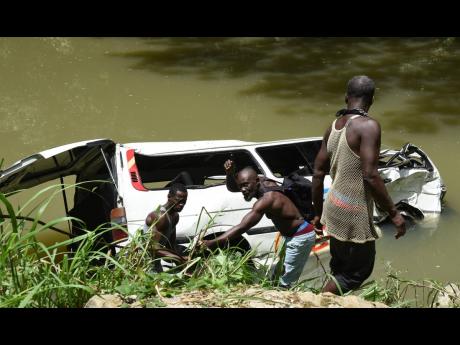 Divers hook chains to the Toyota Hiace minibus that plunged into the Rio Cobre after a traffic crash along the Bog Walk Gorge in June. One woman died in the mishap.