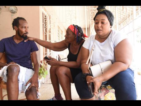 Romario Smikle (left) friend of Derrick Coley and Brianna Kerr who died along Mountain View Avenue in Kingston on Friday, sits with Violet Reid (centre) mother of Coley, and wife Antoinette McGregor.