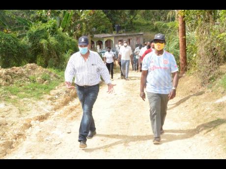 Minister of Local Government and Rural Development, Desmond McKenzie (right), and Minister of State and Member of Parliament for St James Southern, Homer Davis, tour the community of Copperwood last Friday.

 
