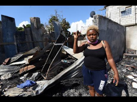 Faith Whyte walks through the rubble of the remains of her house after it was destroyed by fire last Monday night. Her dwelling was among seven destroyed in a section of Naggo Head, St Catherine called Israel.