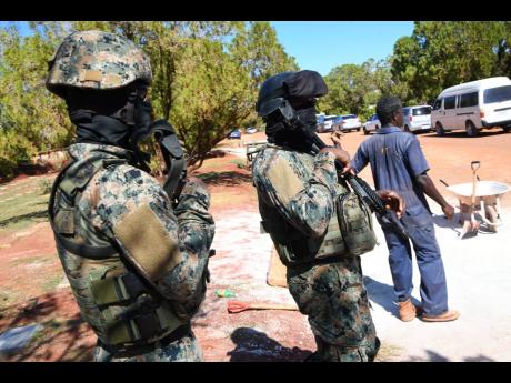 Soldiers keep a close watch of the proceedings at the funeral for Christopher ‘Dog Paw’ Linton at the Dovecot Memorial Gardens in St Catherine last Friday.