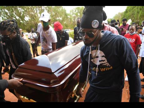 Pallbearers carry the coffin bearing the remains of Christopher ‘Dog Paw’ Linton to its final resting place at Dovecot Memorial Gardens in St Catherine last Friday.