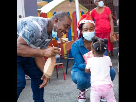 Digicel’s Public Relations Executive, Jody-Ann Fearon, hands over Christmas gifts to a toddler at the Franklyn Town Church of God Christmas treat held on the church grounds. Over 50 children received Christmas gifts, ice cream, pizza, and a goodie bag, thanks to a partnership with Digicel and the Digicel Foundation. 