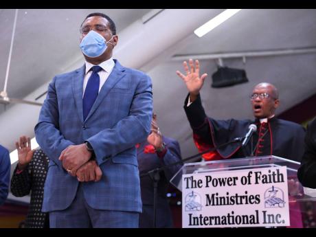 Archbishop of Kingston Kenneth Richards praying for the nation’s leaders during yesterday’s National Day of prayer held at the Power of Faith Ministries in Portmore. In the foreground is Prime Minister Andrew Holness.