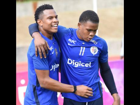 Tarick Ximines (left) and Marlon Pennicooke  of Jamaica College celebrate after Ximines scored his team’s second goal against Charlie Smith High during yesterday’s ISSA-Digicel  Manning Cup semi-final match at the Stadium East field.