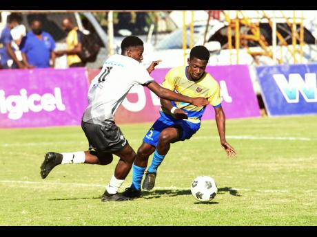 Vere Technical High School’s Omarion Walters (left) rushes in on St Elizabeth Technical High School’s Jeffery Henry during their ISSA Ben Francis Knockout Cup match at the STETHS Sports Complex in Santa Cruz, St Elizabeth yesterday.