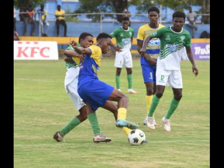 St Elizabeth Technical High’s (STETHS) Michael Jerman (second left) shields the ball from  Frome Technical’s  Nicardo Saunders  during yesterday’s Ben Francis KO match at the STETHS Sports Complex in Santa Cruz. Looking on at  right is Dujon Brown of Frome. 