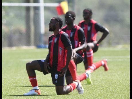 Arnett Gardens players kneel in protest of crime and violence in Jamaica at the start of their Jamaica Premier League game against Cavalier at the UWI-JFF Captain Horace Burrell Centre of Excellence in St Andrew on Sunday.