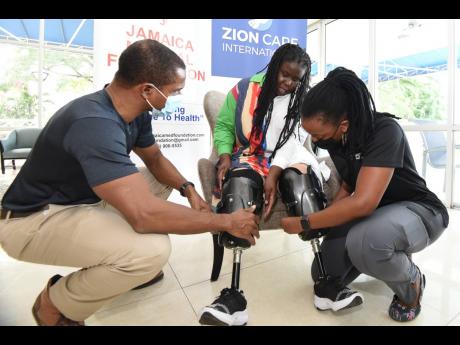 Credit: Kenyon Hemans Dr Rory Dixon (left) senior medical officer of the Sir John Golding Rehab Centre, and Suzanne Watts (right) from Stride Prosthetics in Barbados assist Cara Moore with adjusting her new prosthetics.