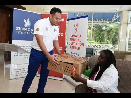 Credit: Kenyon Hemans Dayne Patterson, Hi-Pro business development manager, hands over 100 baby chickens to Moore to help restart her chicken rearing business.