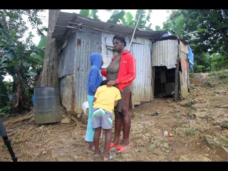 Williams with two of her children outside of their rundown dwelling.