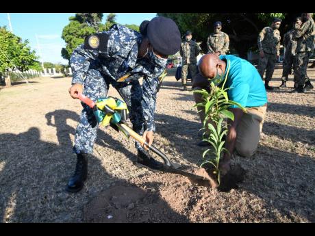 Credit: Rudolph Brown Chief of Defence Staff, Rear Admiral Antonette Wemyss Gorman, (left) plants a tree with the assistance of Ainsley Henry, CEO and Conservator of Forests of the Forestry Department. About 15 trees were planted at the newly constructed ‘Cannon Ball entrance’ and on the grounds of the Jamaica Defence Force’s headquarters in Kingston on Monday.