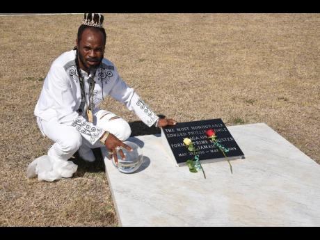 L.A. Lewis, with his crystal ball, at the grave of former prime minister Edward Seaga at National Heroes Park in Kingston yesterday.