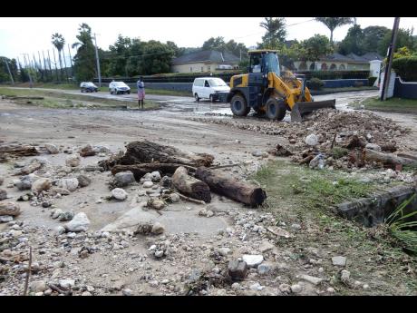 A National Works Agency-contracted operator clears a roadway in Runaway Bay, St Ann, after floodwaters receded on Tuesday. 