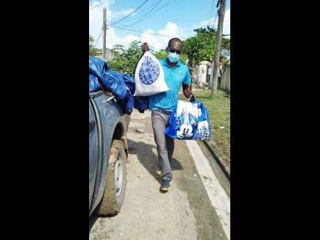 A Food For the Poor worker delivers relief packages for flood victims in St Mary.