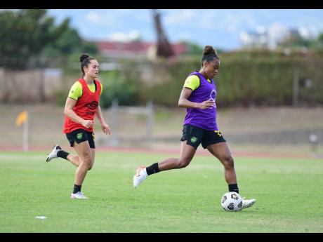 Credit: Gladstone Taylor Allyson Swaby (right) prepares to kick the ball at the Reggae Girlz training session at Stadium East.