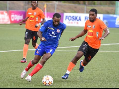 Dunbeholden’s vice-captain Fabion McCarthy (left) dribbles away from Tivoli Gardens FC’s Rickardo Oldham during their Jamaica Premier League match at the UWI-JFF Centre of Excellence yesterday.