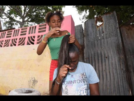 Kenneva Davis giving her cousin Shenay Barr a top knot bun hairstyle.