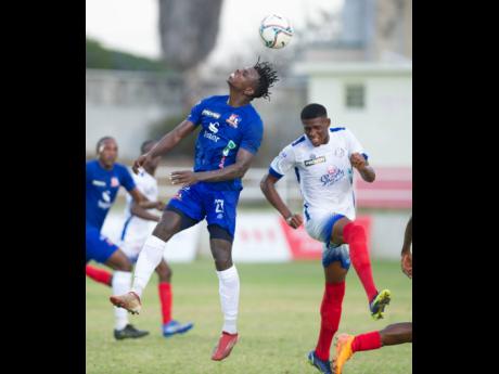 Credit: Ricardo Makyn Portmore United’s Gawain Austin (right) gets close as Dunbeholden’s Peter McGregor heads the ball away during their Jamaica Premier League match at Sabina Park in Kingston yesterday.