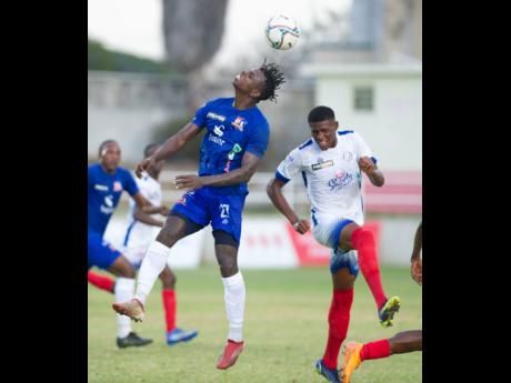 Portmore United’s Gawain Austin (right) gets close as Dunbeholden’s Peter McGregor heads the ball away during their Jamaica Premier League match at Sabina Park in Kingston yesterday.