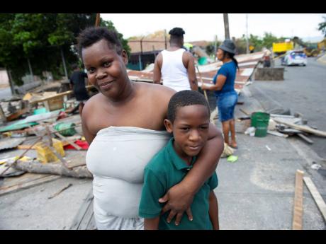 Credit: Ricardo Makyn Crab vendor Shana-Kay Palmer standing with her nephew, Ranchi Edwards, at Heroes Circle in Kingston where stalls used by the vendors are being torn down to make way for new ones.