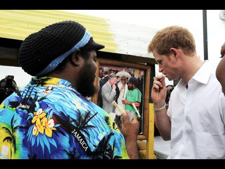 In this 2012 photo, sugarcane vendor Carlos Morgan (left) of Falmouth, Trelawny, shows Prince Harry a photograph he took with his father, Prince Charles, eating a piece of the sweet treat during a 2008 royal visit to the town. Morgan also treated the young prince to sugarcane during his tour of the Falmouth Pier.