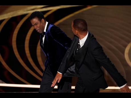 Will Smith (right) hits presenter Chris Rock on stage while presenting the award for best documentary feature at the Oscars at the Dolby Theatre
in Los Angeles last night.