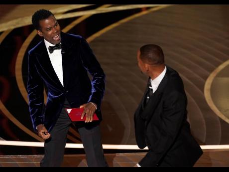 Chris Rock (left) reacts after being hit on stage by Will Smith. (AP Photo/Chris Pizzello)
