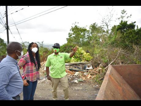 Minister of Local Government and Rural Development, Desmond McKenzie (right), discusses measures to address garbage pile-up along the Bellefield Hill main road in Manchester with Mayor of Mandeville, Councillor Donovan Mitchell, and Member of Parliament for Manchester Central, Rhoda Moy Crawford, during a tour of the constituency last week.