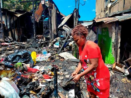 Charmaine Barclay, 45, sorts through the rubble of her home at Chestnut Lane, west Kingston, after yesterday’s fire.