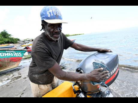 Below: Jason Bailey shines his boat engine.  He said that despite an increase in prices, people are still coming out in their numbers to buy fish.