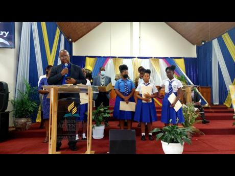 Linval Christie, principal of Papine High School, gives a tribute joined by students. 
