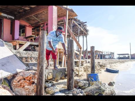 Kingsley Johnson, owner of Any Money One Stop at Hellshire Beach in St Catherine, points to the sea waters that have now reached the doorsteps of his business establishment.