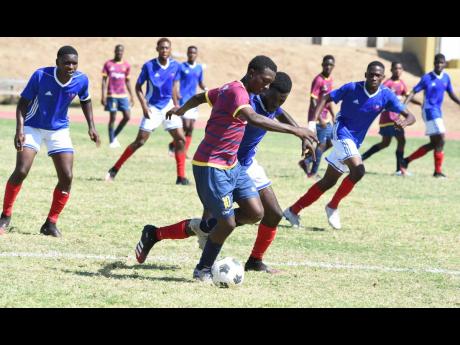 St Andrew Technical High School’s Omar Laing (centre), takes on Camperdown High players during a Manning Cup match last November.