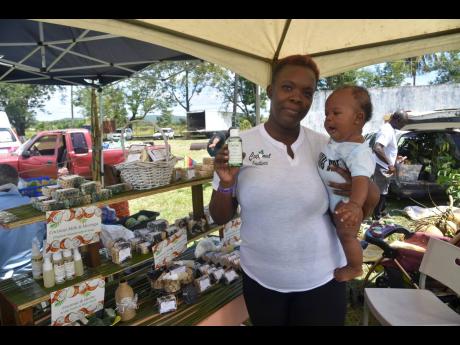 Roxanne Harrison holds baby My’khal-Dre Martin while displaying a bottle of sativa arimatheraph cannabis oil, one of her products under the Coconut Creationz banner.