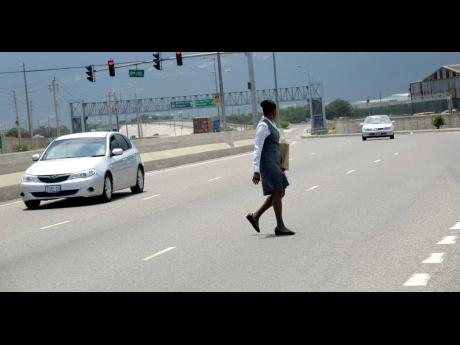 A woman makes her way across the busy Marcus Garvey Drive instead of using the overhead bridge that was constructed for the safety of pedestrians.