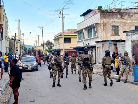Members of the Jamaica Defence Force try to maintain calm in Denham Town last week after a pregnant woman was reportedly kicked in the stomach by one of their colleagues.