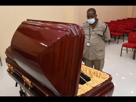 Inspector Mark Watson, a Mighty Diamonds fan, views the body of Fitzroy ‘Bunny Diamond’ Simpson at Perry’s Funeral Home, Job Lane, Spanish Town, on  Wednesday.