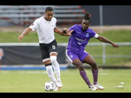 Christopher Pearson (left) of Cavalier SC drives the ball past Steeven Saba of Violette AC during yesterday’s Flow Concacaf Caribbean Club Championship match held at the Estadio Cibao stadium in Santiago de los Caballeros,  Dominican Republic.