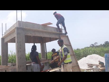 Volunteers work on the construction of a bus stop at the Little London High School on Monday (May 23), which was the Labour Day parish project for Westmoreland.