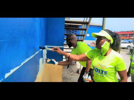 Jamaica Public Service Foundation Programme Officer Allaine Harvey (left), paints a section of the Charles Gordon Market in Montego Bay, St James along with Administrative Assistant at the JPS in Westmoreland/St Elizabeth Jullite Reeves, on Labour Day.