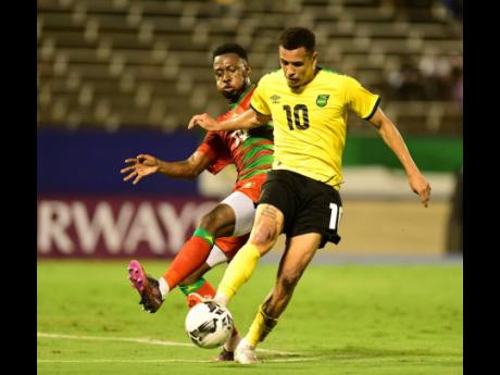 Jamaica’s Ravel Morrison (right) dribbles clear of Suriname’s Shaquille Pinas during the Jamaica versus Suriname Concacaf Nations League Group A  match at the National Stadium last night.