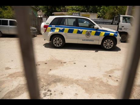 A police service vehicle is parked in proximity to the area where three men were shot dead in Pleasant View, Bull Bay, St Andrew early Sunday morning.