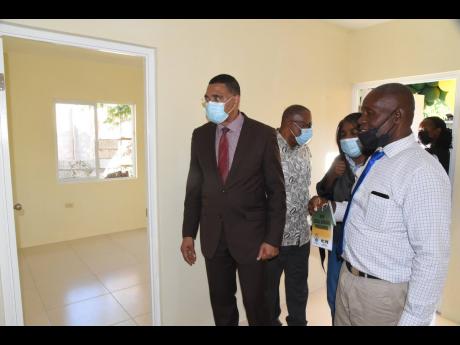 Prime Minister Andrew Holness (left) tours the newly built two-bedroom house provided to Collington Graham (right) under the New Social Housing Programme.