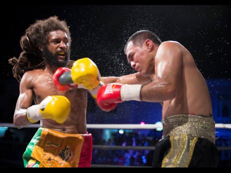 Jamaica’s Headley ‘The Light’ Scott delivers a hard left to Mexico’s Jesus Laguna during a Gloves Over Guns fight night at the Ambassador Theatre in Trench Town, Kingston, on Saturday, July 13, 2019.